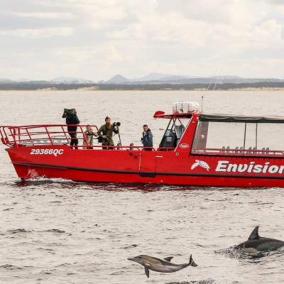 a red and white boat sitting next to a body of water